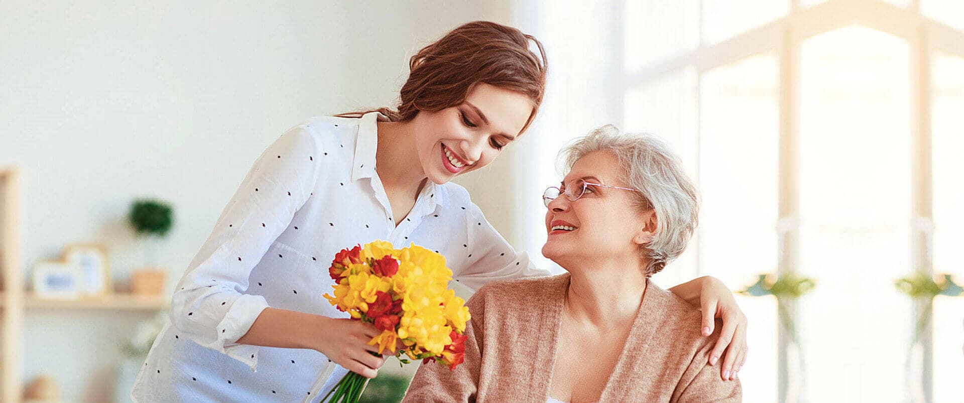 caregiver giving flower to senior woman