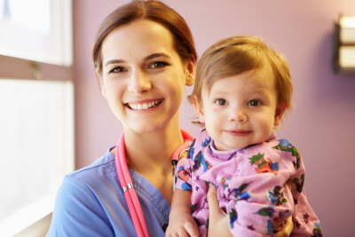 young girl held by pediatric nurse